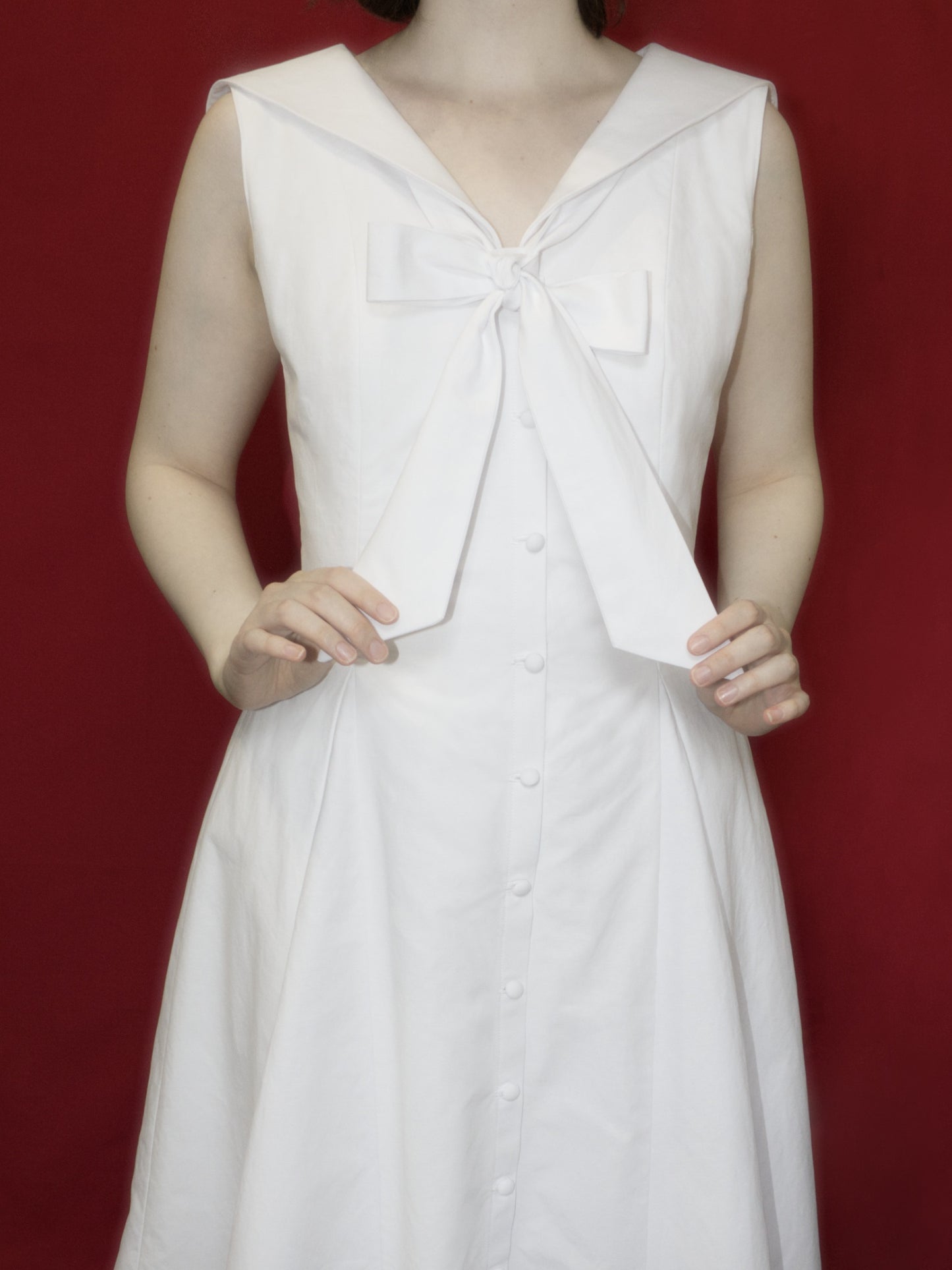 Detail view showing the neck tie and fabric covered buttons down the centre front.
