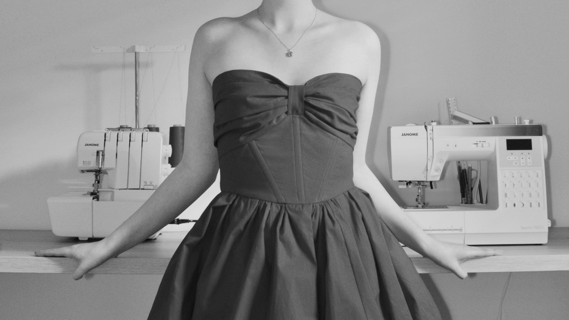 Woman wearing a strapless dress in a sewing room with sewing machines.