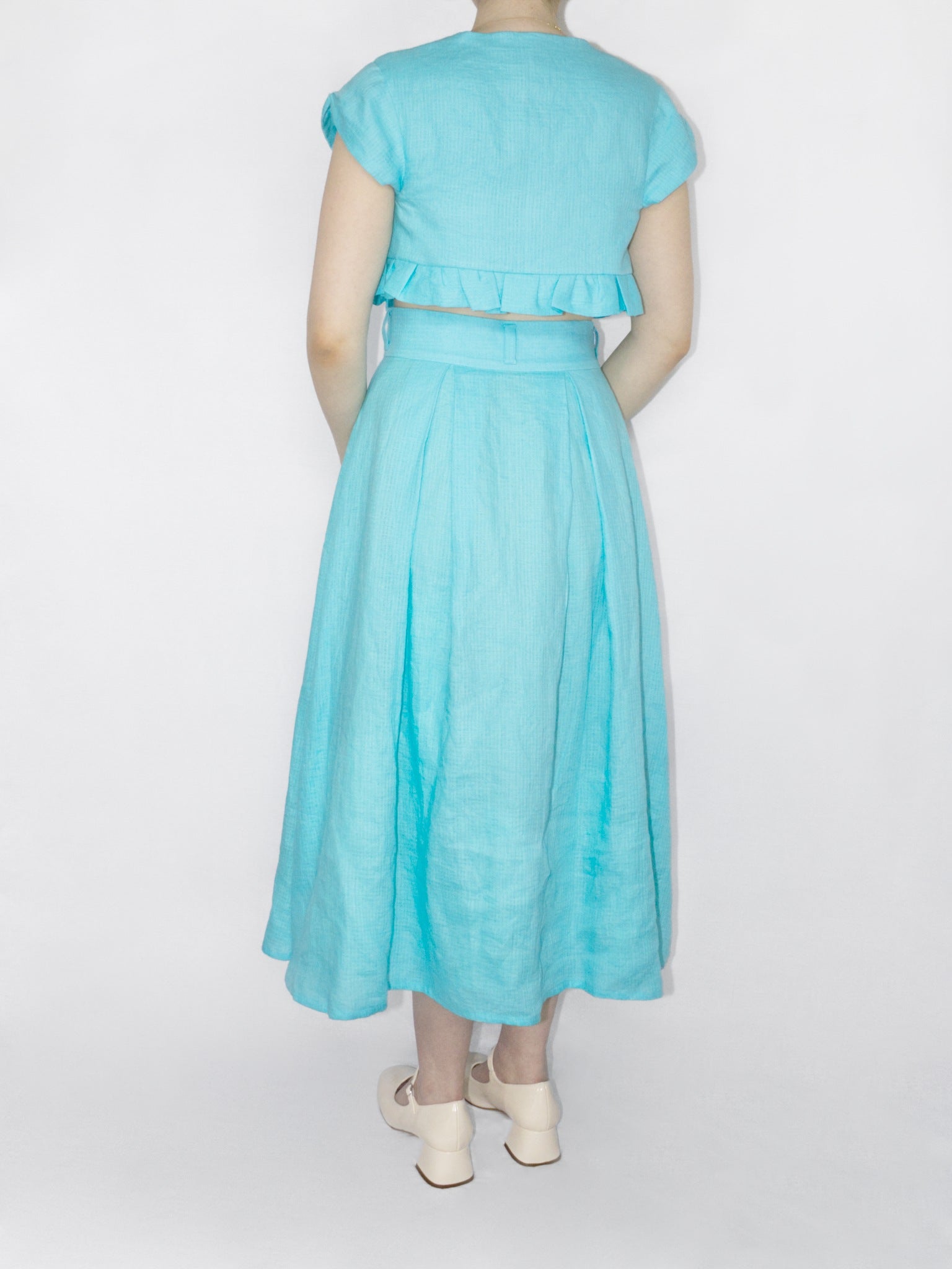 Back view showing the high back neck on the top and three belt loops on the skirts waistband.