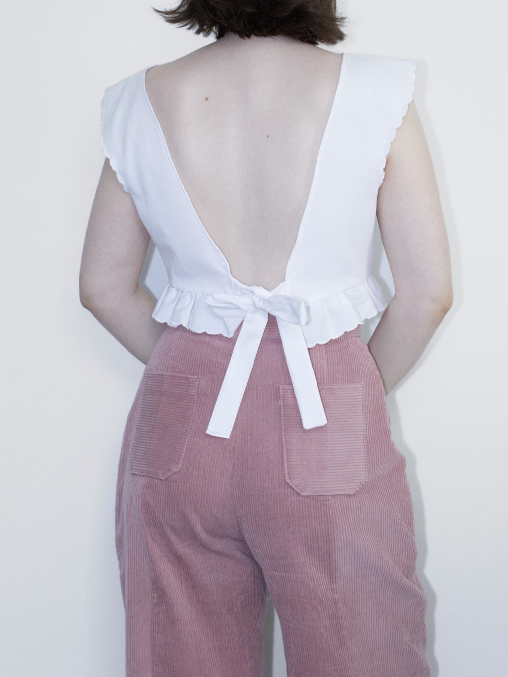 Back view showing a V-shaped backless cut and ties tied into a bow towards the bottom.