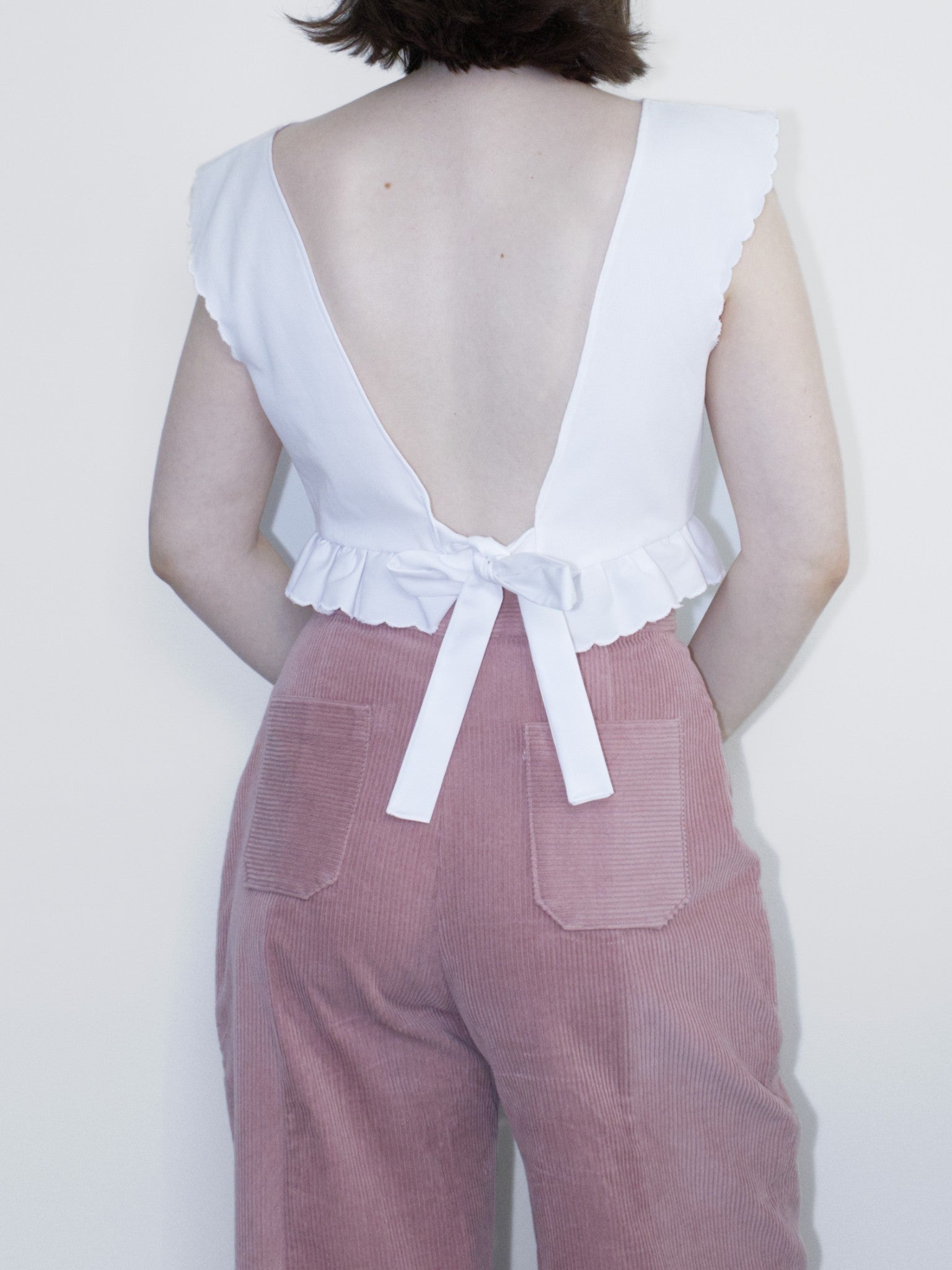 Back view showing a V-shaped backless cut and ties tied into a bow towards the bottom.