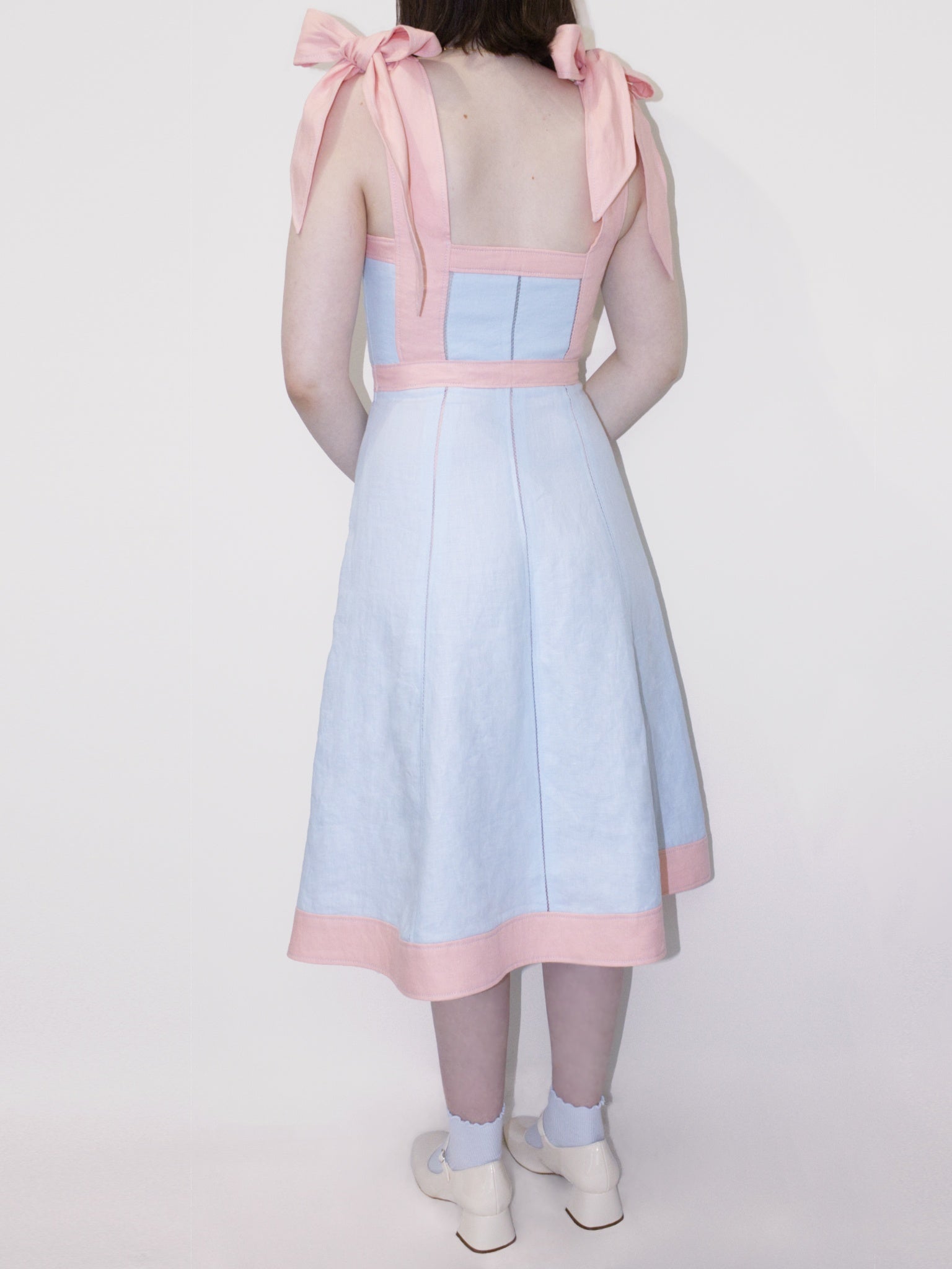 Back view of the dress showing the back neckline going straight across at mid back level. There are three vertical rows of open stitching in the back. 