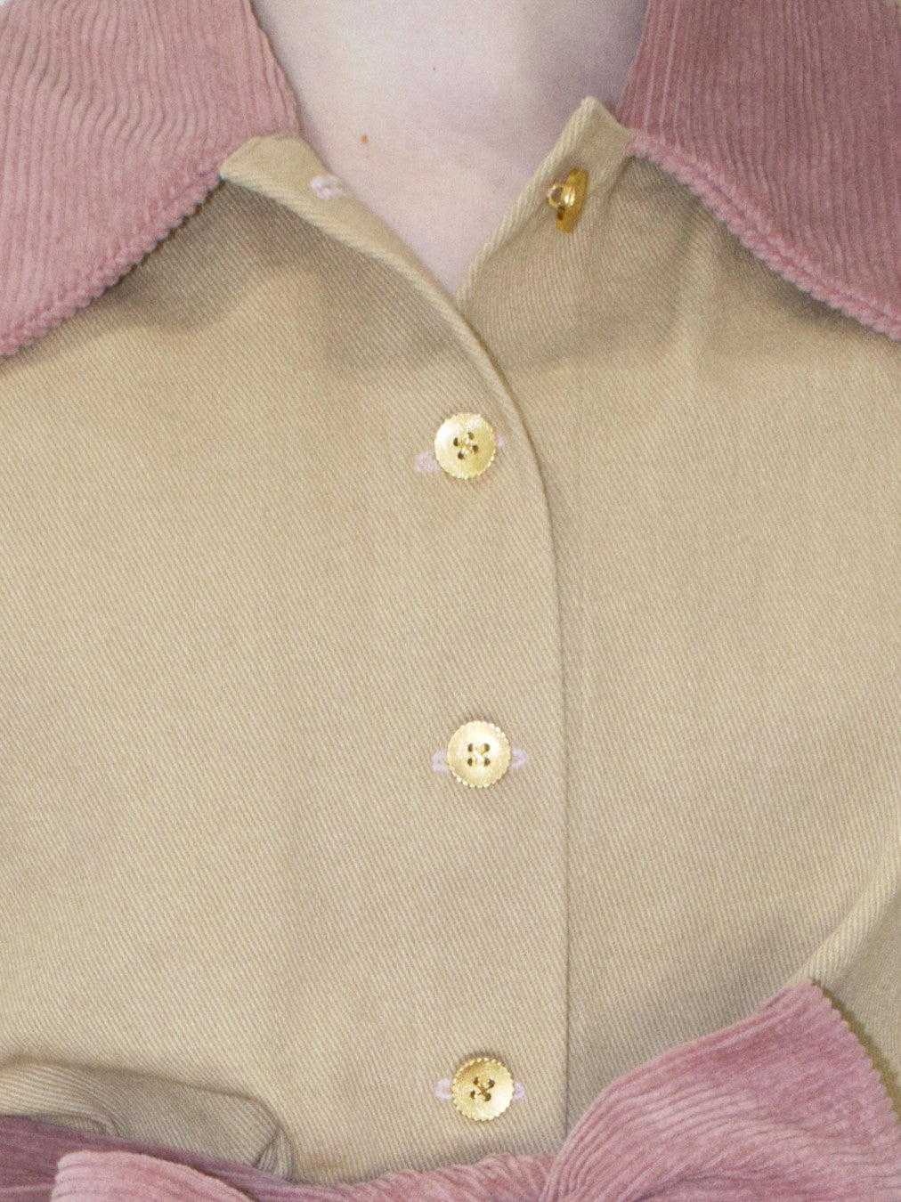 Detail view of gold buttons with scalloped edges on the jacket.