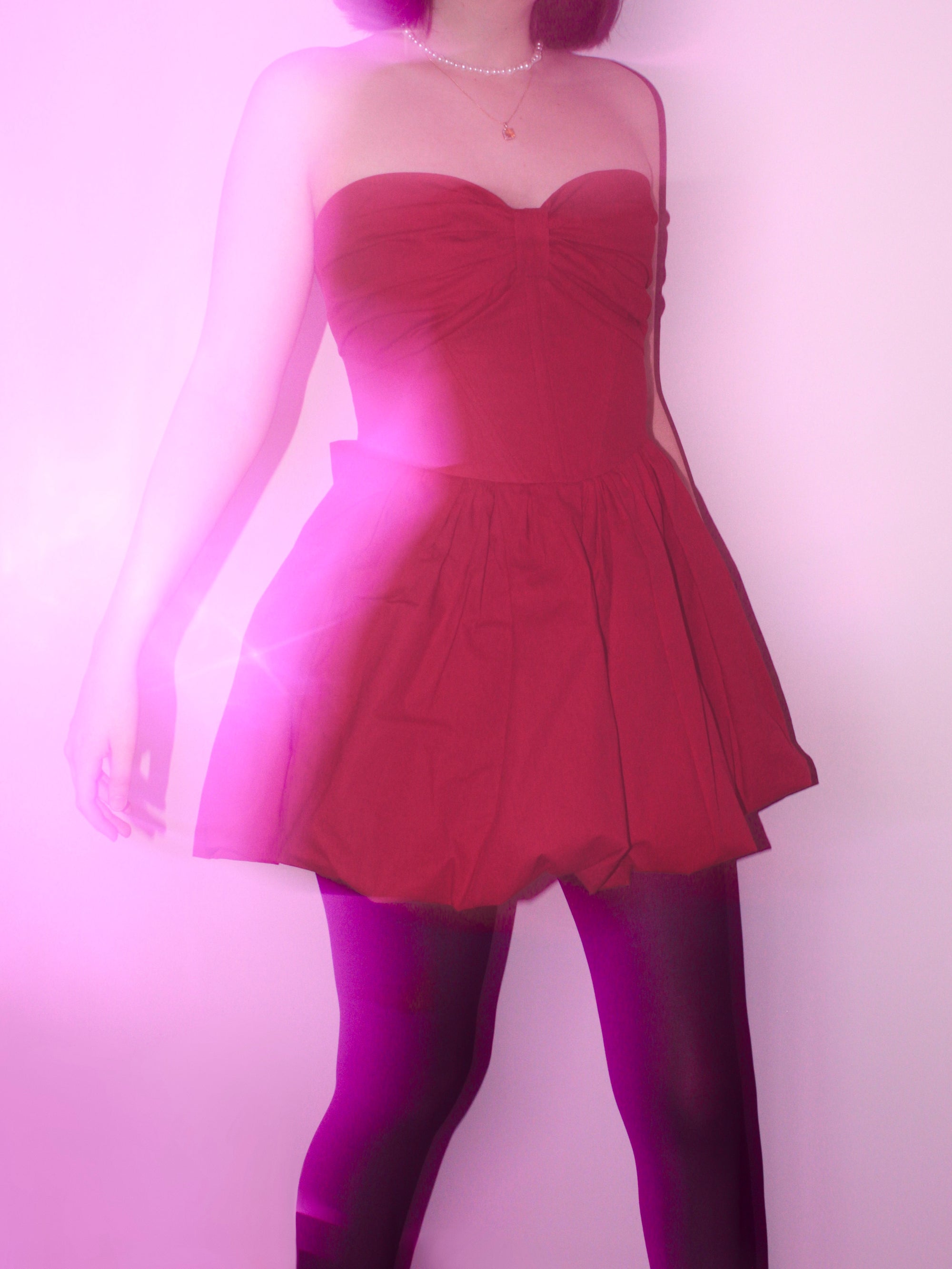 A motion blur image of a woman wearing a strapless red mini dress with bow detail.